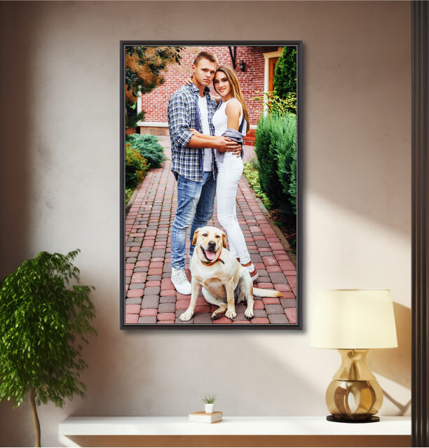  Canvas portrait photo of a couple standing on a brick path with their Labrador retriever sitting in front of them, framed and hung on a warmly lit wall above a white console table