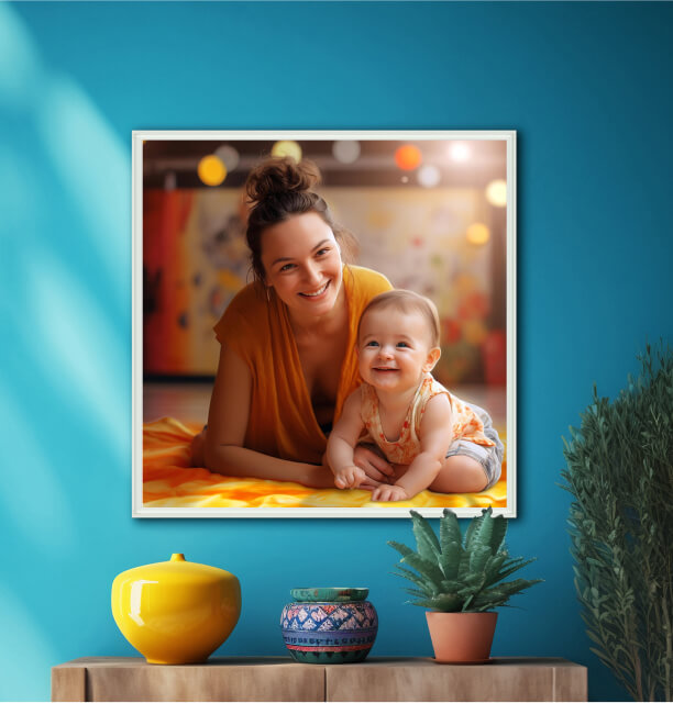 Framed photo of a smiling mother and baby lying on a colorful blanket against a vibrant blue wall.